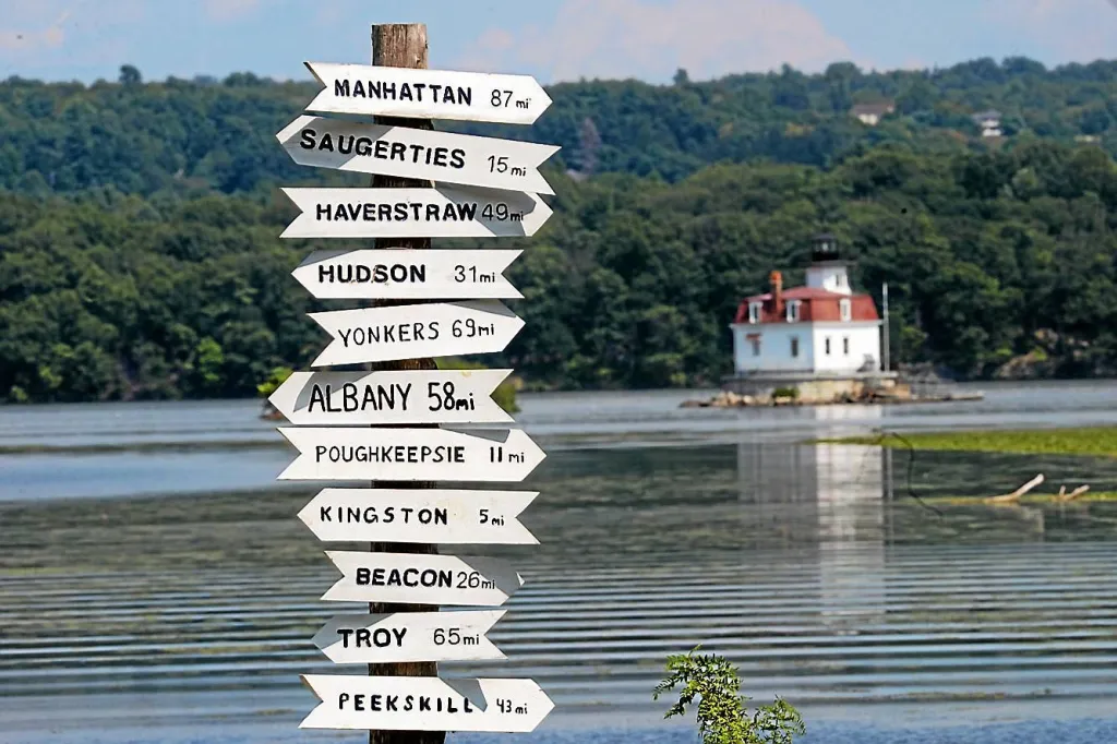 Lighthouse at Esopus Meadow Preserve against a clear sky, surrounded by natural greenery.