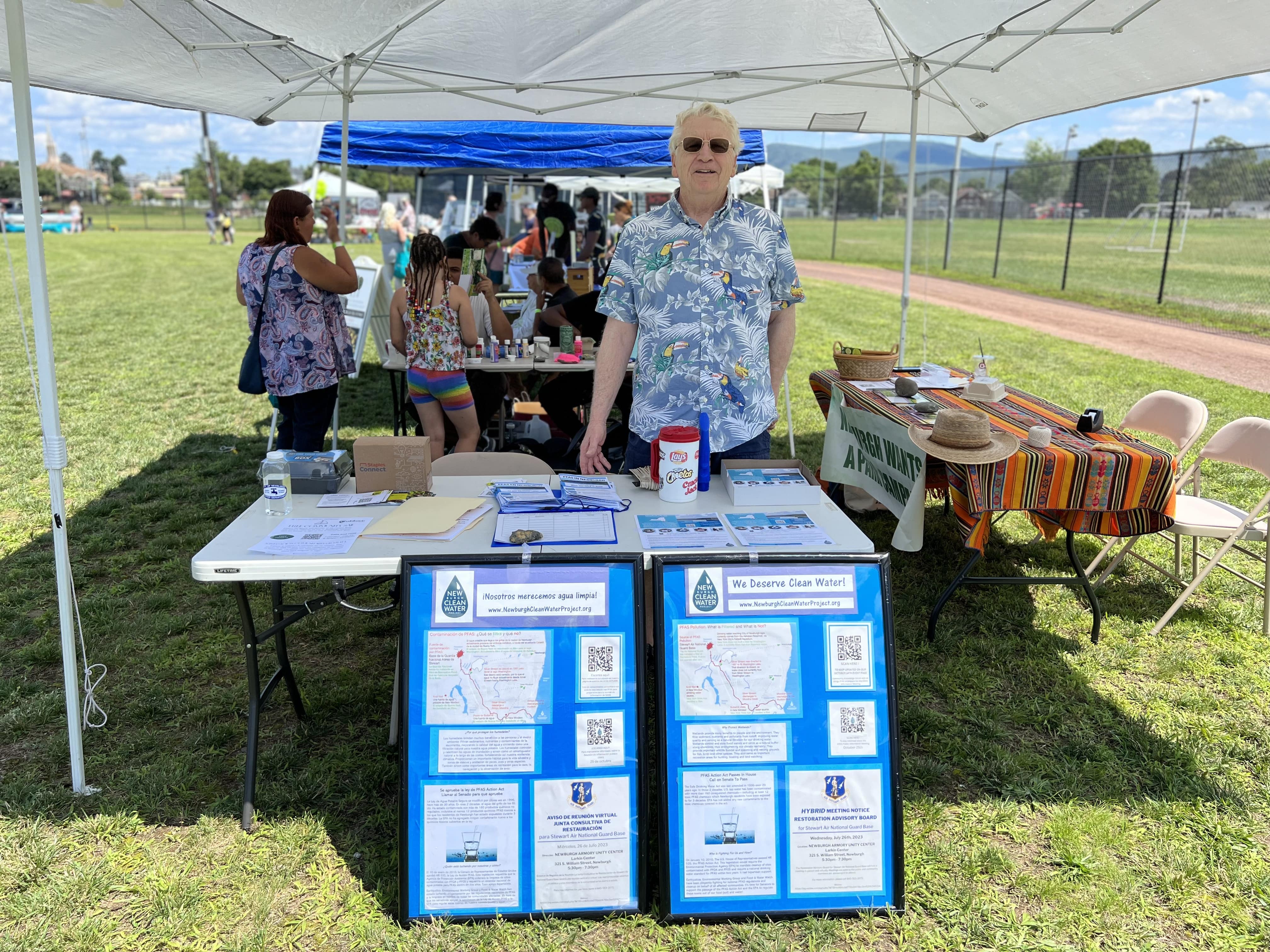 Bill Fetter standing behind a table representing the Newburgh Clean Water Project and the Quassaick Creek Watershed Alliance informing residents of the upcoming Restoration Advisory Board meeting 