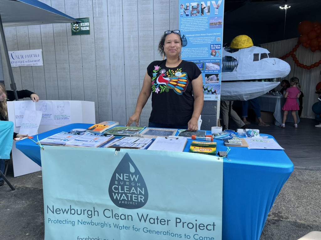 The Newburgh Clean Water Project table and banner at Clean Water Community Day, with the plastic-bottle sculpture behind